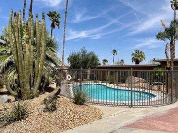 Cathedral City apartment for rent - A pool surrounded by a fence and cacti.