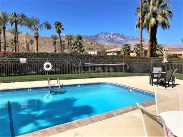 Cathedral City apartment for rent - a swimming pool with palm trees and mountains in the background