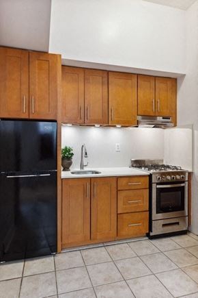 Brooklyn apartment for rent - a kitchen with wooden cabinets and a black refrigerator