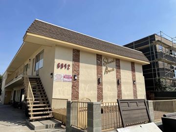 Van Nuys apartment for rent - A small building with a brown roof and a sign that reads "Shark" is in front of a construction site.