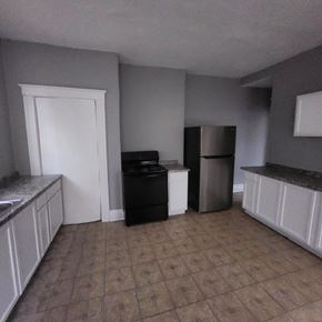 Cincinnati apartment for rent - A kitchen with a black fridge and white cabinets.