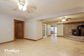 Douglasville house for rent - a large empty living room with a fireplace and a ceiling fan