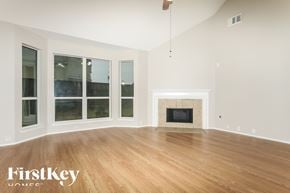 Humble house for rent - A large empty room with a fireplace and wooden floors.