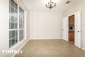Humble house for rent - A room with a chandelier, a window with a view of trees, and a door leading to a kitchen.