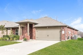 Katy house for rent - a brick house with a garage door and a lawn