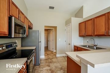 Cape Coral house for rent - a kitchen with black appliances and wooden cabinets and white counter tops