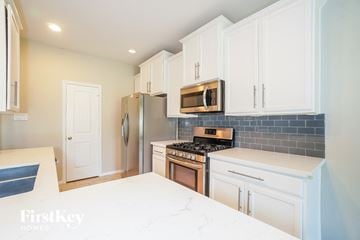 Spring house for rent - a kitchen with white cabinets and stainless steel appliances