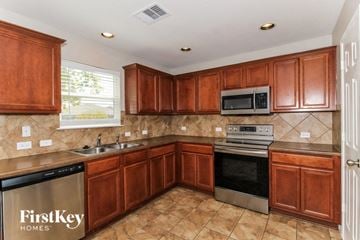 New Braunfels house for rent - A kitchen with brown cabinets and a FirstKey Homes dishwasher.