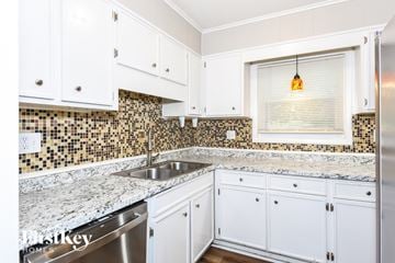 Kennesaw house for rent - A kitchen with white cabinets and a marble countertop.