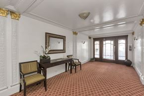 San Francisco apartment for rent - A room with a red tiled floor and a white wall with a mirror and a chair.