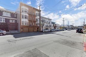 San Francisco apartment for rent - A street view of a residential area with buildings on the left and cars parked on the right.