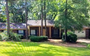 Tallahassee house for rent - A house with a green lawn and trees in front.