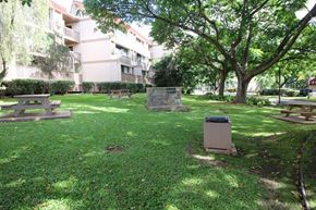 Waianae apartment for rent - A grassy area with a bench and a trash can in front of a building.