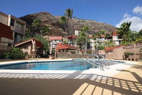 Waianae apartment for rent - A pool in front of a mountain with a building in the background.