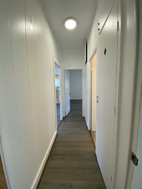 Honolulu apartment for rent - A long hallway with white walls and wood floors.