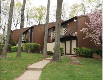 Staten Island apartment for rent - A brown building with a balcony and a tree in front of it.