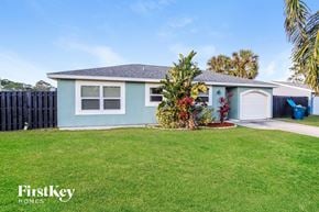 Palm Bay house for rent - a light blue house with a lawn and a garage