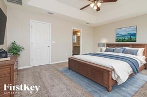 Jacksonville house for rent - A bedroom with a large bed, a ceiling fan, and a painting on the wall.