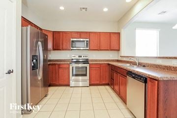 Goodyear house for rent - a kitchen with wooden cabinets and stainless steel appliances