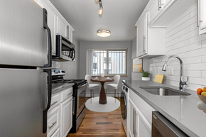 Denver apartment for rent - a kitchen with white cabinets and black appliances and a table