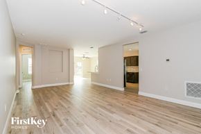 Cape Coral house for rent - A spacious room with wooden flooring and white walls, with a door on the left and a window on the right.