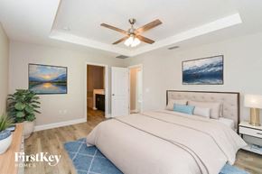 Cape Coral house for rent - A bedroom with a large bed, a ceiling fan, and two pictures on the wall.