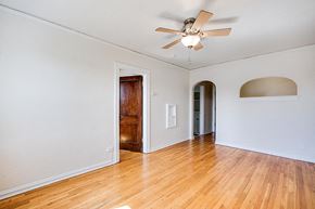 Denver apartment for rent - A room with a ceiling fan and wooden floors.