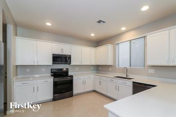 Mesa house for rent - A kitchen with white cabinets and appliances, and a FirstKey Homes logo.
