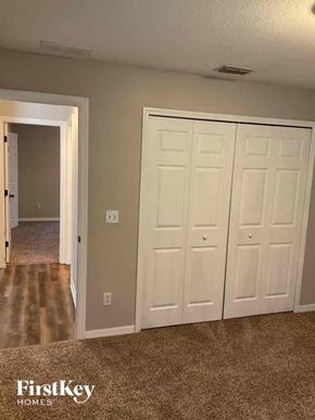 Deltona house for rent - an empty bedroom with two closets and a hallway with a door to a bathroom