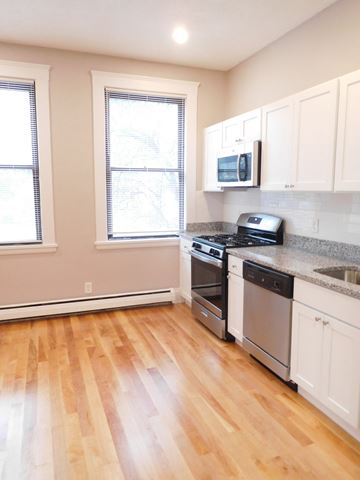Allston apartment for rent - a kitchen with white cabinets and a stove and a microwave