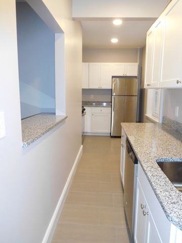 Brighton apartment for rent - a kitchen with white cabinets and granite counter tops and a stainless steel refrigerator