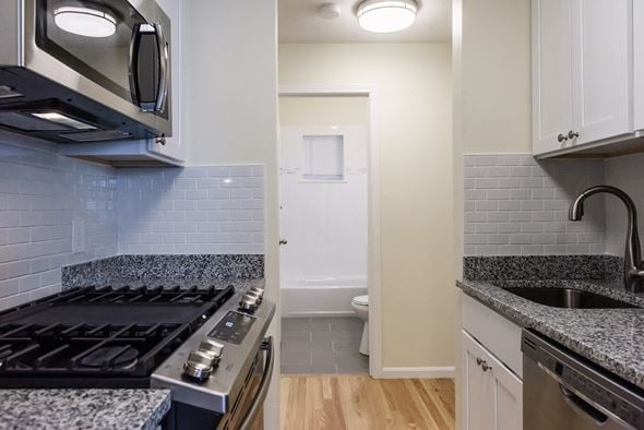 Allston apartment for rent - Galley Kitchen with White Cabinets, Stainless Appliances, Gas Stove, Granite Counters, White Subway Tiles