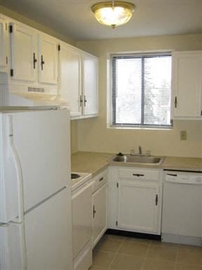 Worcester apartment for rent - a kitchen with white cabinets and a sink and a refrigerator
