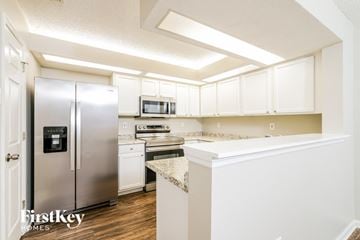 Jacksonville house for rent - a kitchen with white cabinets and a stainless steel refrigerator