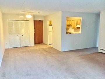 Quincy apartment for rent - an empty living room with a mirror and a refrigerator