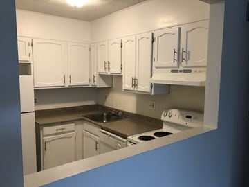 Quincy apartment for rent - a kitchen with white cabinets and a sink and a stove