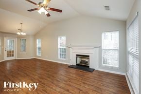 Gainesville house for rent - A spacious room with a fireplace and a ceiling fan.