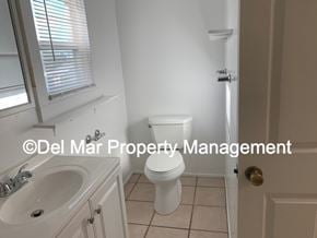 Grover Beach apartment for rent - A white toilet in a small bathroom with a sink and a window.