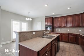 Humble house for rent - a kitchen with wood cabinets and an island with a sink