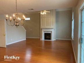 Cumming house for rent - A large empty room with a fireplace and a chandelier.