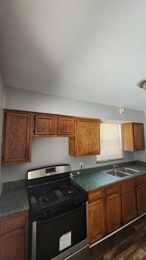 Cincinnati house for rent - A kitchen with wooden cabinets and a black stove top oven.