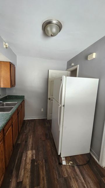 Cincinnati house for rent - A white refrigerator stands in a kitchen with wooden floors and a green counter.