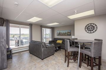 Red Deer apartment for rent - A living room with a grey couch, a table and a clock on the wall.