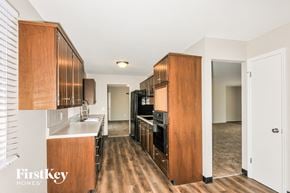 St Louis house for rent - a kitchen with wooden cabinets and white counter tops and a black stove and refrigerator