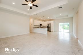 North Port house for rent - an empty living room and kitchen with a ceiling fan
