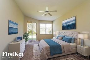 Lehigh Acres house for rent - A bedroom with a large bed and a ceiling fan.