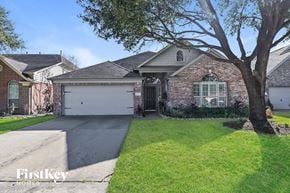 Cypress house for rent - a brick house with a white garage door and a tree