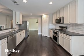 Cypress house for rent - a kitchen with white cabinets and stainless steel appliances
