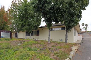 Vista apartment for rent - a white building with trees and a road in front of it