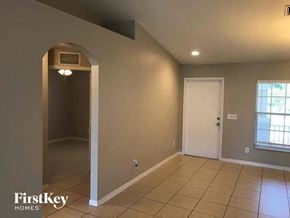 Lehigh Acres house for rent - an empty living room with a door to a hallway and a tiled floor